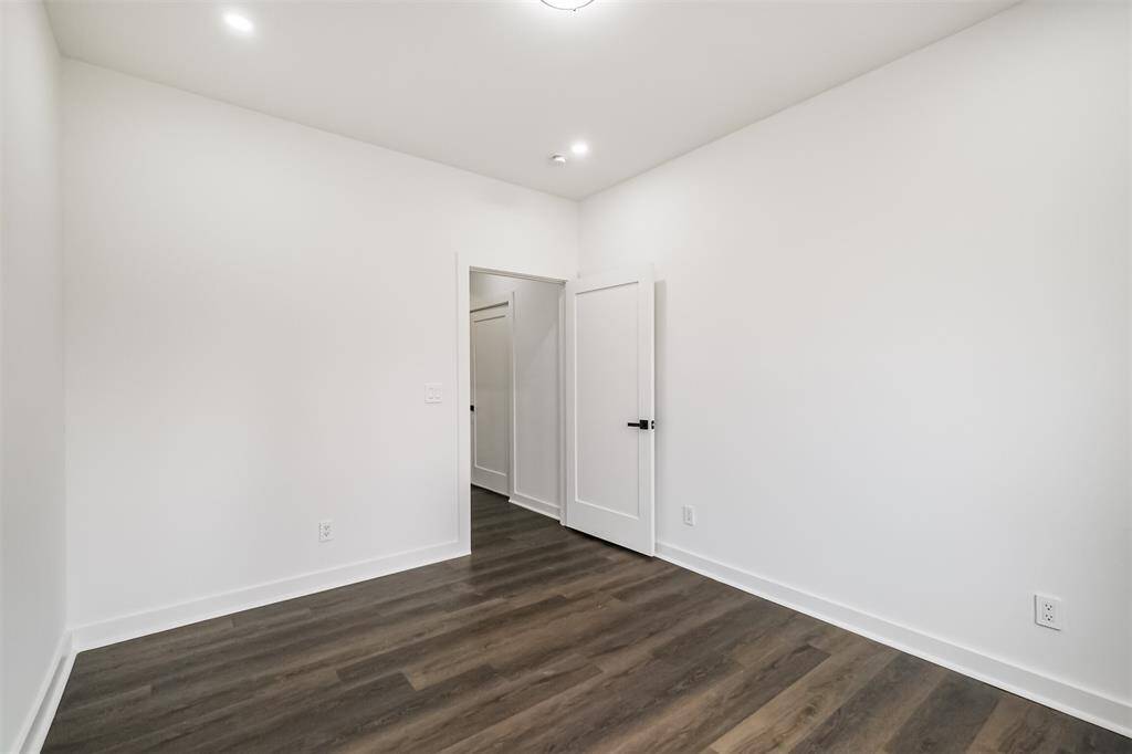 This room features bright white walls, two large windows offering natural light, and dark wood flooring, creating a modern and airy atmosphere.