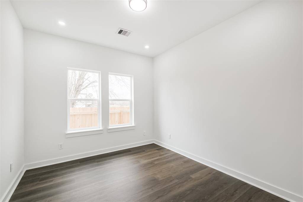 This photo shows a spacious walk-in closet with white walls and shelving, offering ample hanging and storage space. The closet is well-lit, enhancing its clean and organized appearance.