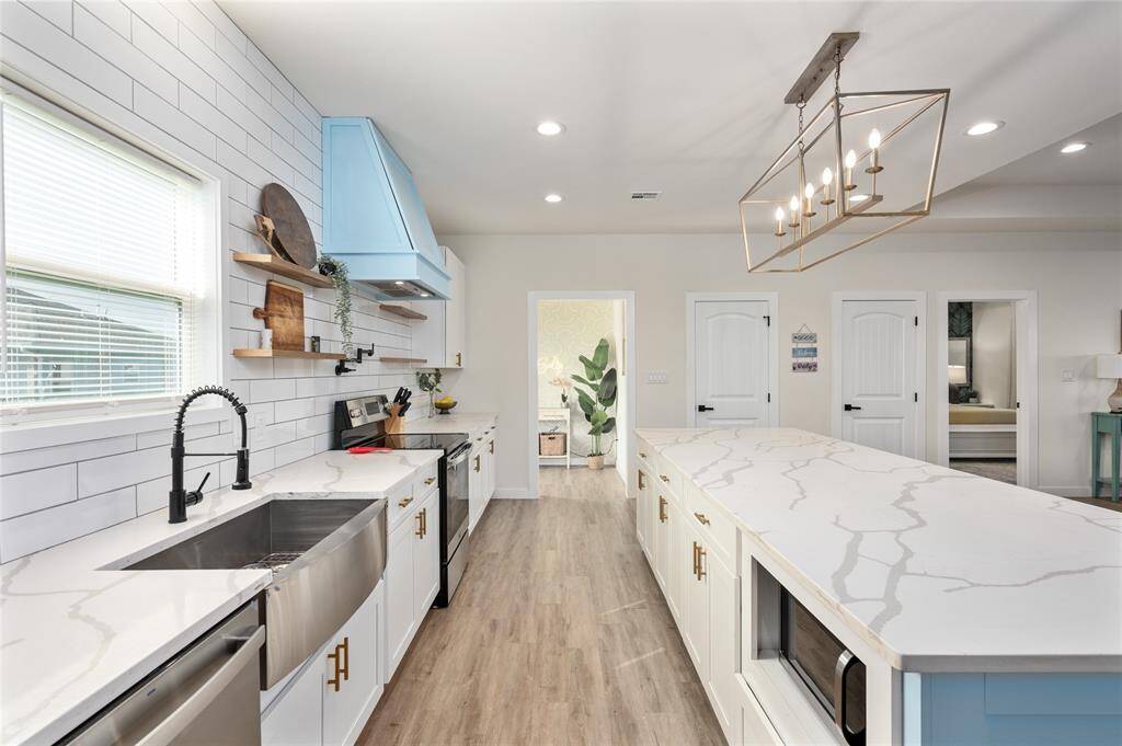 The accent color on the kitchen island carriers over to the custom range vent hood for cohesive, costal look.