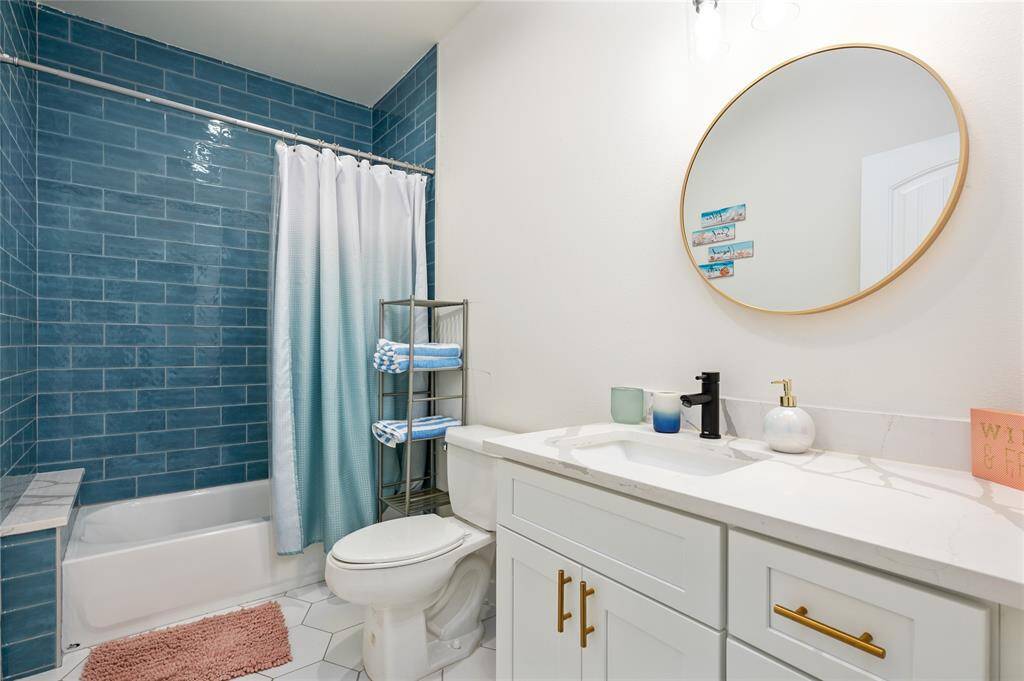 Aqua floor-to-ceiling shower tile adds a wow factor to this modern bathroom. The tub-shower combo even features a quartz shelf that matches the countertop.