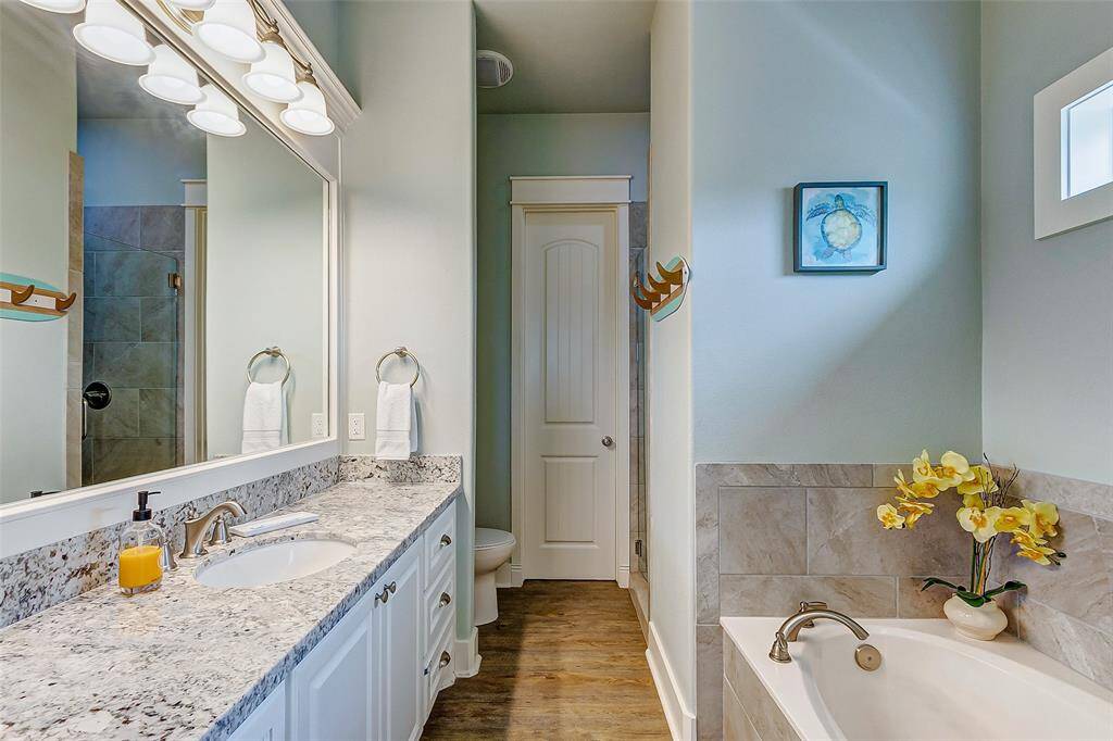 Primary bathroom features soaking tub, walk-in shower, and large granite-topped vanity with plenty of storage.