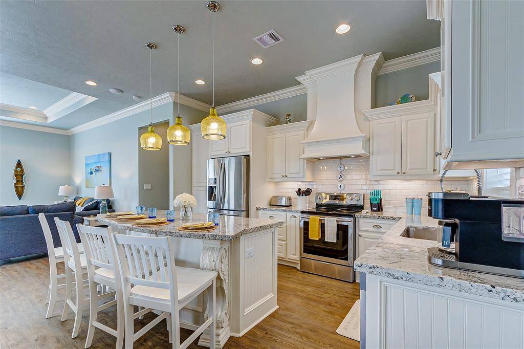 The kitchen features stainless steel appliances, granite countertops, breakfast bar, and custom cabinetry with range vent hood