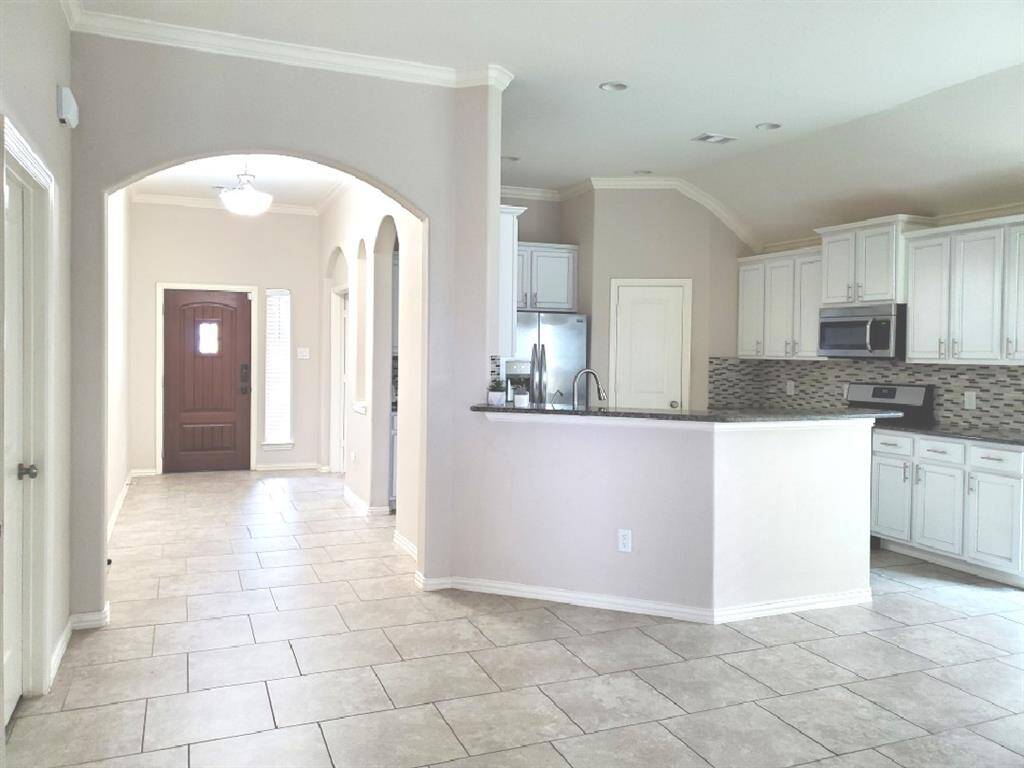 This living room features a spacious and modern design. It has a sleek fireplace, complemented by built-in shelves. Large windows provide ample natural light, and the ceiling fan adds comfort.