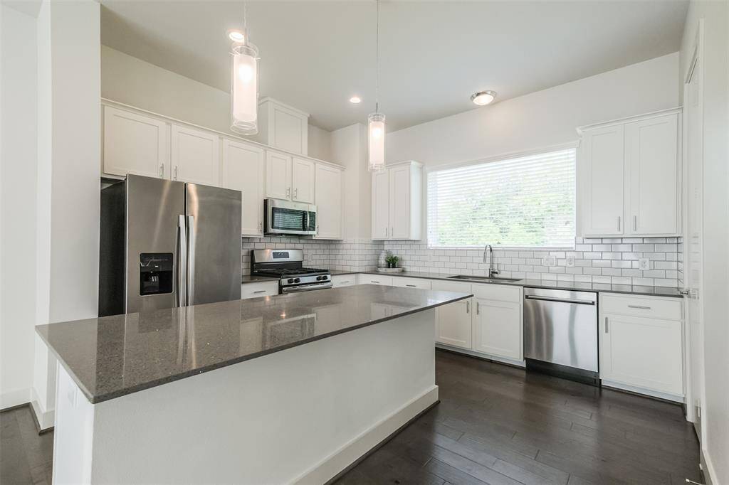 Step into a world of modern sophistication in this spacious kitchen, boasting stainless steel appliances that add an element of sleek style to the space. With chic modern lighting, sleek quartz countertops, a convenient built-in microwave, and ample white cabinets for all your storage needs. This exquisite kitchen is sure to be the heart of your home.