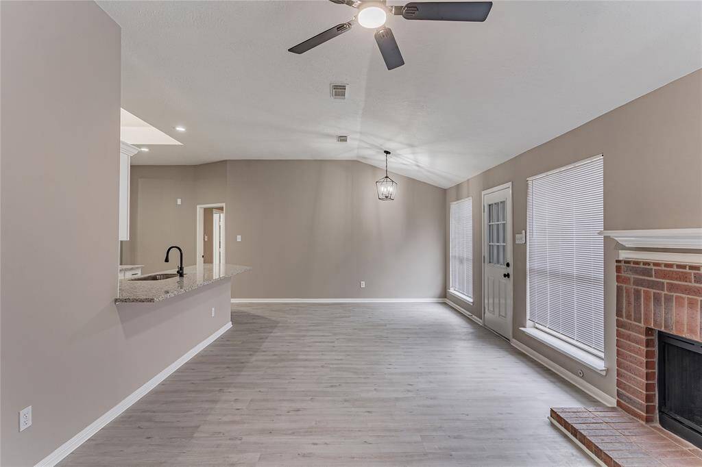 Spacious living area featuring sleek flooring, a cozy fireplace, and abundant natural light, perfect for family game nights.