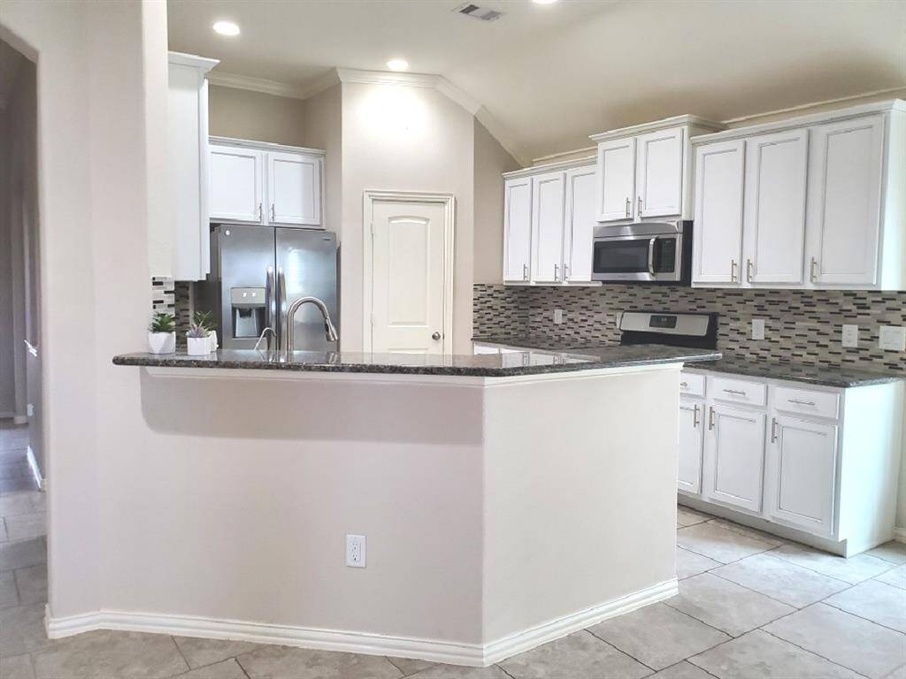This living room features a spacious and modern design. It has a sleek fireplace, complemented by built-in shelves. Large windows provide ample natural light, and the ceiling fan adds comfort.