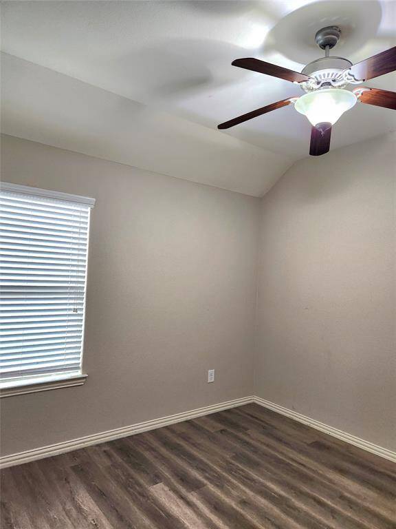 This living room features a spacious and modern design. It has a sleek fireplace, complemented by built-in shelves. Large windows provide ample natural light, and the ceiling fan adds comfort.
