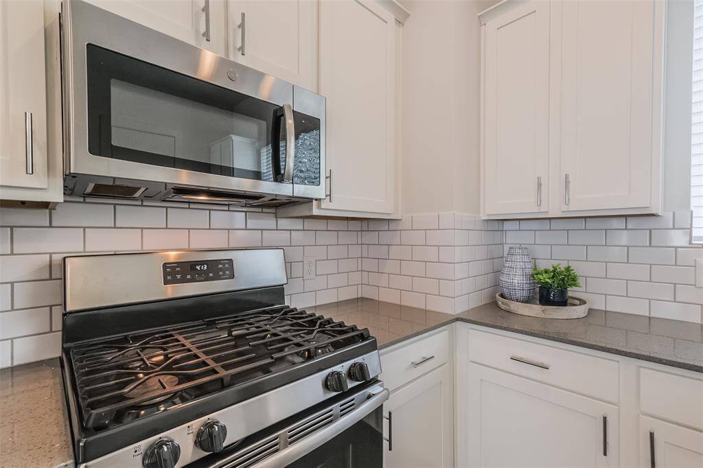Adorned with a sleek white backsplash that brightens the room, a premium gas range for precise cooking, and a convenient built-in microwave for easy meal preparation, this area seamlessly blends style and functionality for an unparalleled culinary experience.