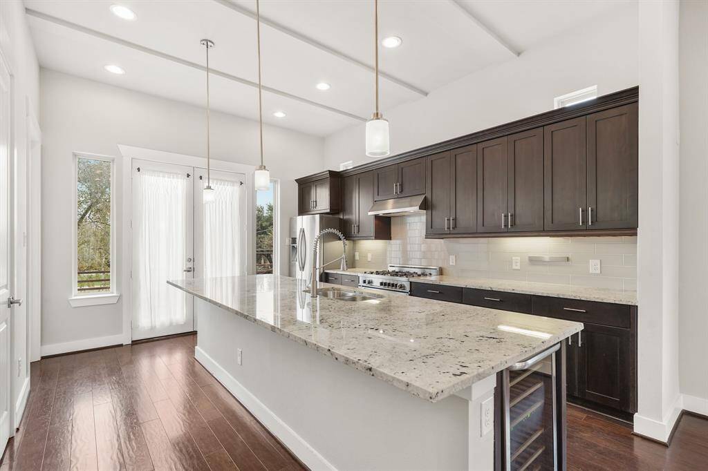 A gourmet kitchen awaits you with this 12' island with pendant lighting & breakfast bar seating! French doors flanked by windows add natural light to this beautiful kitchen and includes a wrought iron balcony overlooking the backyard. Additional features include a high ceiling with recessed lighting & hardwood floors.