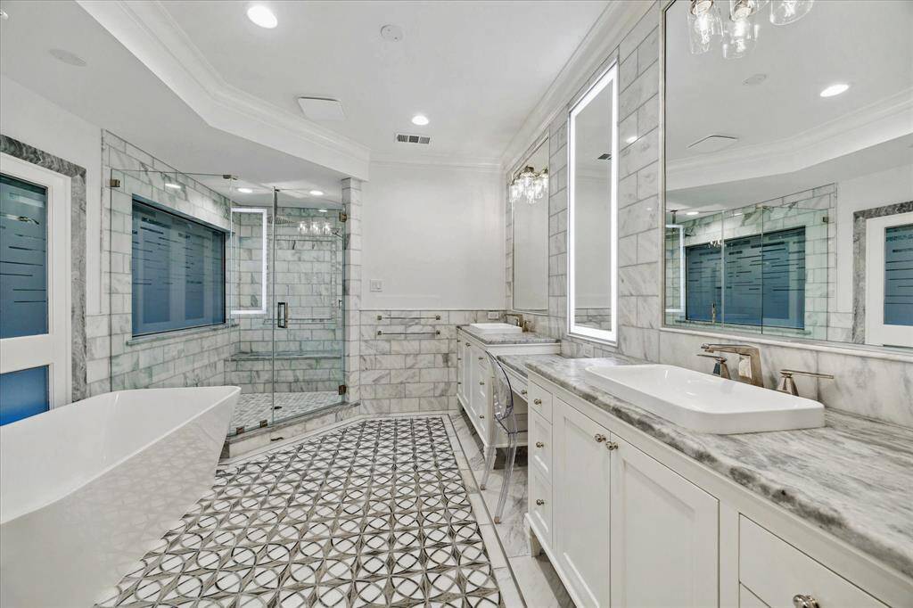 [Primary Bath] Freestanding soaking tub and marble frameless shower with bench seating. Water closet with door.