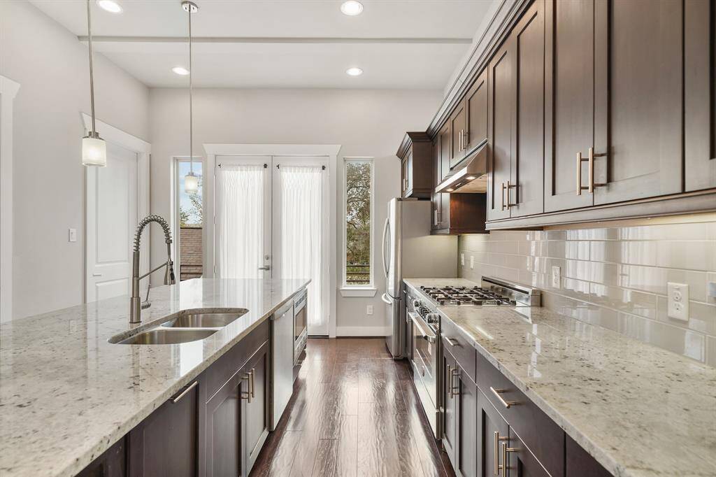 Surrounded by 42" wood-stained cabinetry capped with crown moulding, this kitchen includes granite counter tops and a subway tiled back splash with under-cabinet lighting.