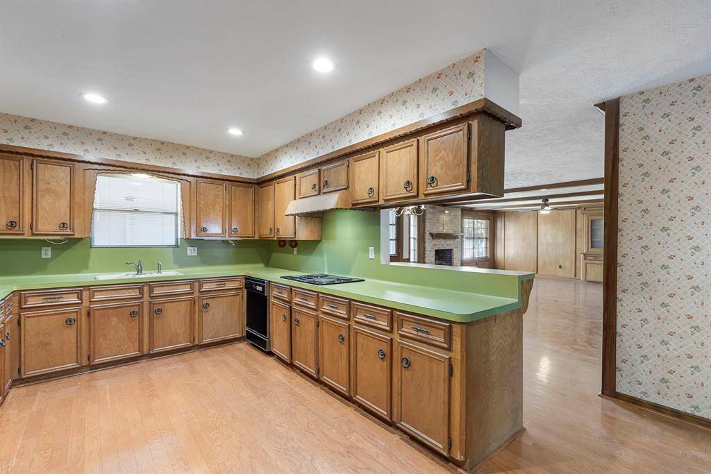 The L-shaped kitchen offers double ovens, an electric cooktop, and a pantry area.