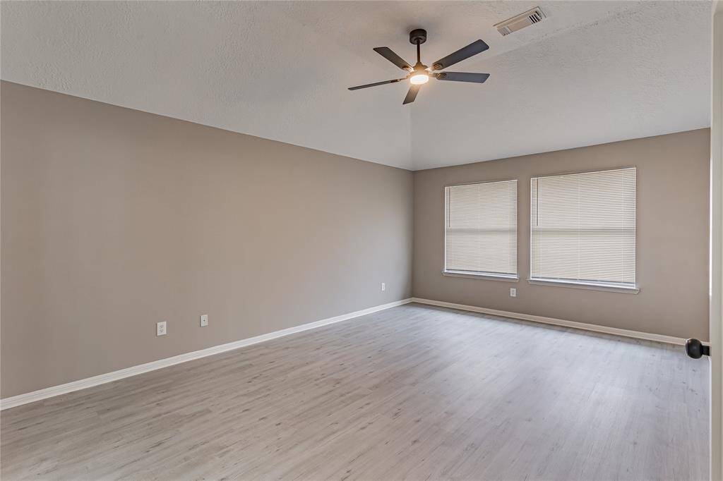 Spacious primary bedroom with modern flooring, ample natural light, and a sleek ceiling fan for comfort and style.