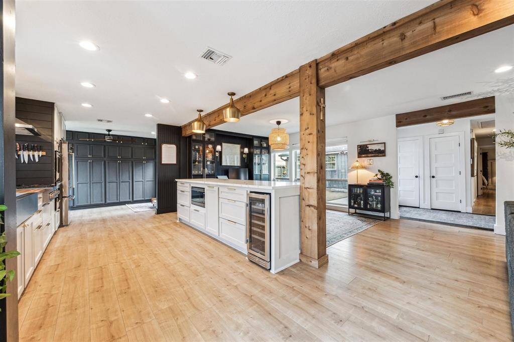 Another view that shows the custom wine fridge, microwave, and the large wall to wall pantry. The pantry storage provides deep shelves to store everything from dry goods to appliances!