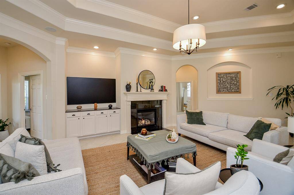 Here is another view of the gas log fireplace and TV area, which will accommodate a large TV. Hallway to the primary suite is to the left and hallway to the right leads to secondary bedrooms as well as the attic access with One Touch electric attic staircase (2024).