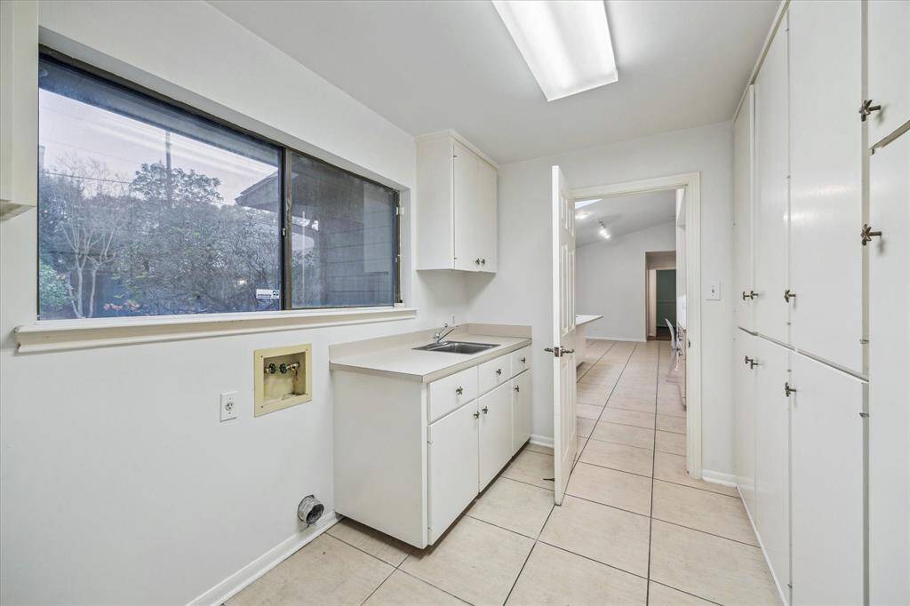 [Utility Room] Highly functional utility room adjacent to the kitchen. Has sink with storage cabinets.