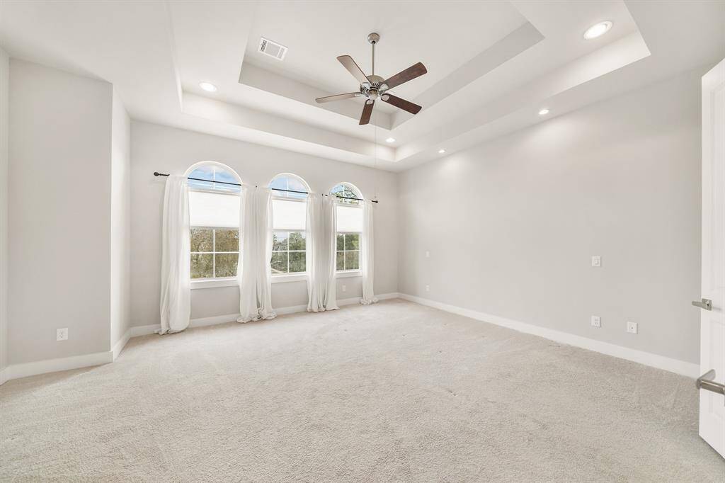 Beautifully designed, the owner's suite with a double tray ceiling includes recessed lighting, a ceiling fan with lighting, arched windows with shades & draperies, individually controlled reading lights & carpet.
