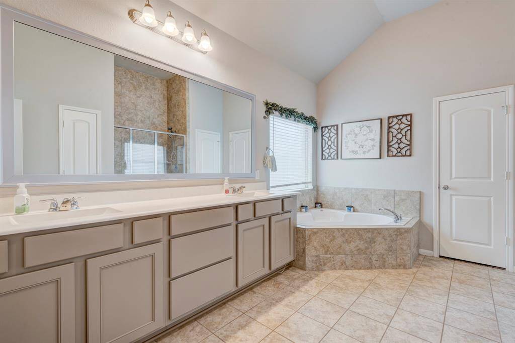 Primary bathroom has plenty of storage, double sinks and a corner soaker tub. The door in the picture is the walk in closet.