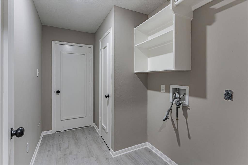 Spacious laundry room with modern shelving and sleek finishes, ready for your washer and dryer setup.