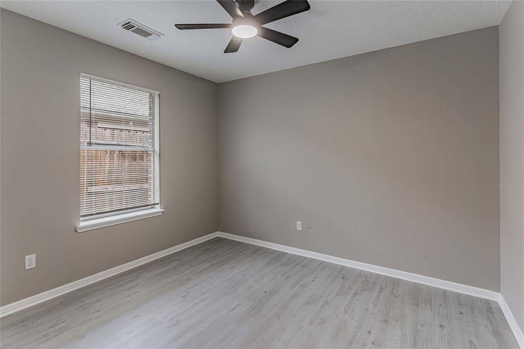Spacious second bedroom with abundant natural light and sleek modern flooring.