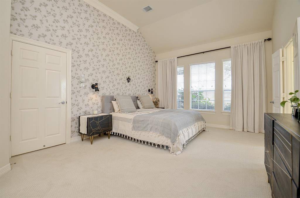 Another view of the primary suite with dual sconce lights above the nightstands and oversize door as a mobility accommodation.