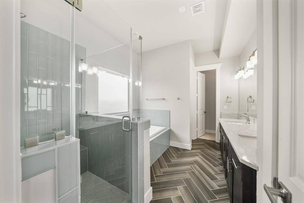 Luxuriously appointed, the owner's bath with a high ceiling is graced by a herringbone patterned tiled floor.