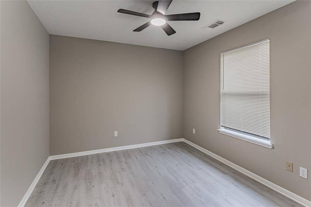 Cozy third bedroom with sleek flooring and a modern ceiling fan, perfect for relaxation or a home office.