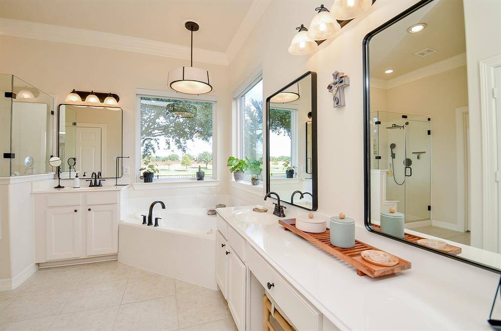 This bathroom features a bright, spacious design with new panoramic windows from Window World (2024) with shades the lower for your privacy.  All faucets are Moen (2024).   The double vanity with modern fixtures, the luxurious bathtub, and glass-enclosed shower all create a relaxing ambiance.