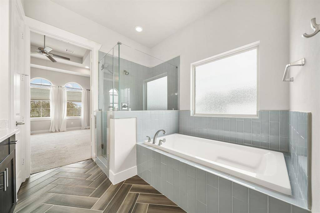 Relax and unwind in the beautiful subway tile surrounded soaking tub with privacy glass window above and nearby walk-in tiled & glass enclosed shower.
