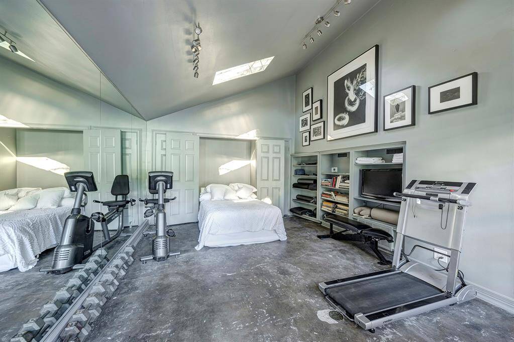 The pool house is a charming and versatile space, featuring a Murphy bed that allows it to easily transform into a guest suite when needed. Currently being used as a workout studio, it offers ample space for exercise equipment or other activities. The room is fully equipped with a bath, adding both convenience and comfort for overnight guests or day-to-day use.