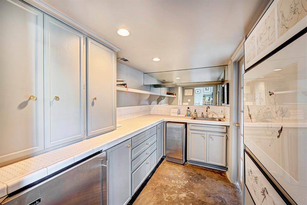 Part of the pool house is thoughtfully equipped with convenient storage, a sink, an ice maker, and a mini refrigerator, making it the perfect spot for poolside entertaining. Whether preparing drinks, storing refreshments, or organizing pool supplies, this space adds a layer of ease and functionality to outdoor gatherings.