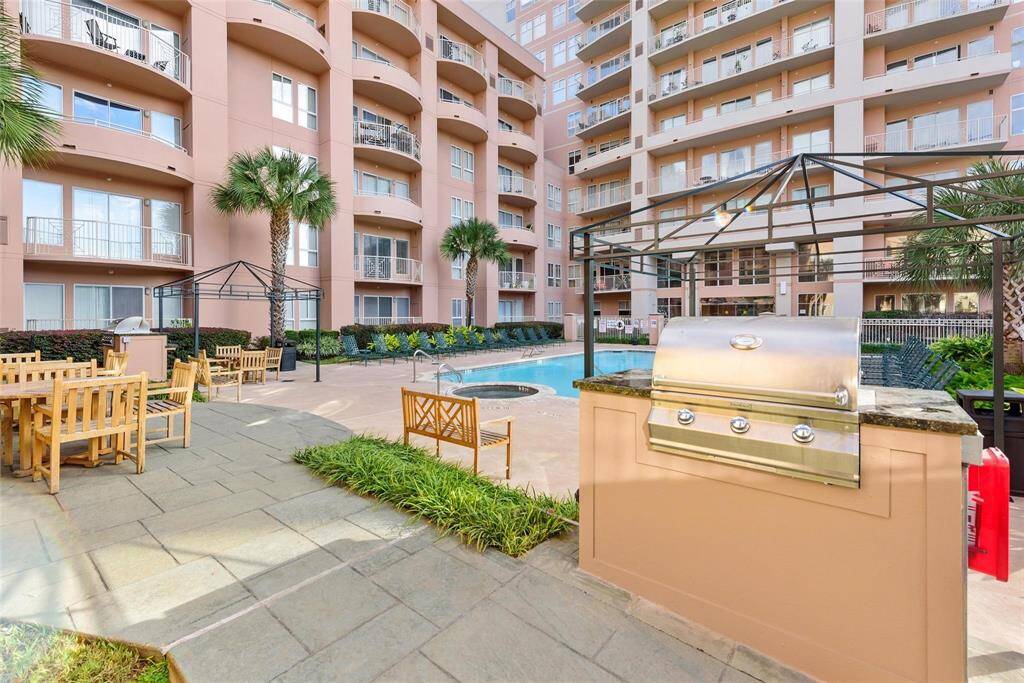 A barbecue grill by the poolside with plenty of seats for dining and lounge chairs to relax.