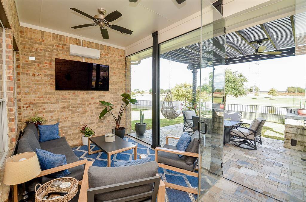 The frameless glass swings open to the outdoor pergola, which features a seating area and an outdoor kitchen.