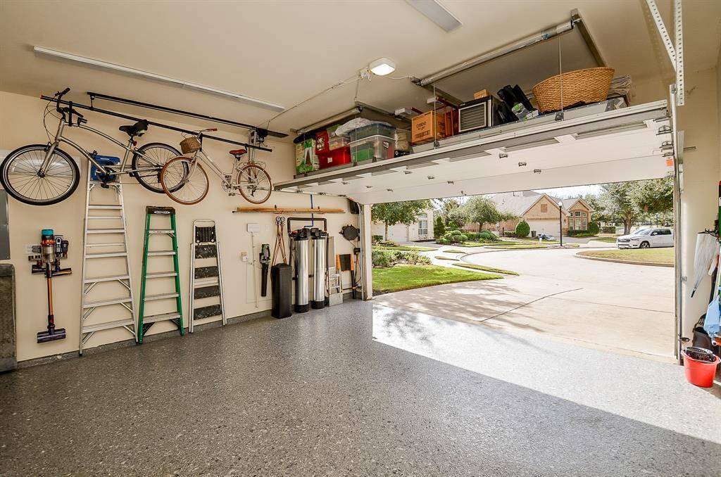 Epoxy floors give this garage space a clean and finished look (2023). New garage door and My Q side mount garage door opener installed in 2022. Notice these overhead storage racks. With a touch of a button, these AUX Lift storage racks raise and lower so keeping your garage tidy is a breeze (2024). The overhead bike racks are also automatic, so keeping the bikes ready to ride encourages your exercise!