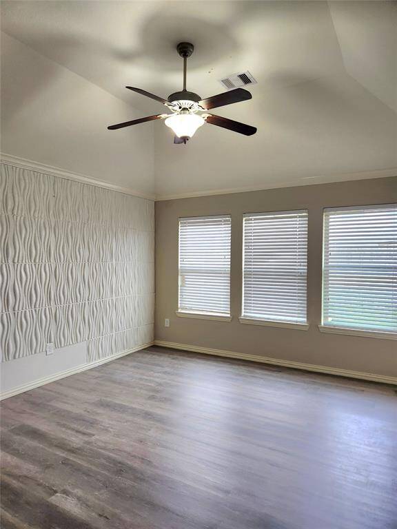 This living room features a spacious and modern design. It has a sleek fireplace, complemented by built-in shelves. Large windows provide ample natural light, and the ceiling fan adds comfort.