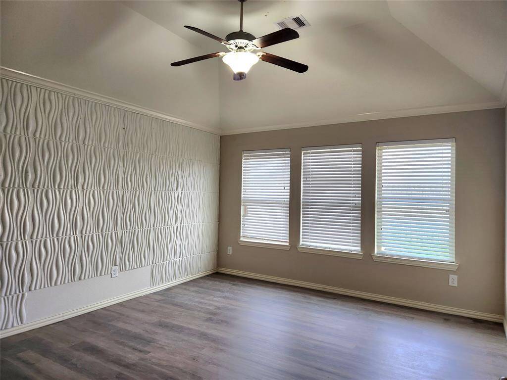 This living room features a spacious and modern design. It has a sleek fireplace, complemented by built-in shelves. Large windows provide ample natural light, and the ceiling fan adds comfort.