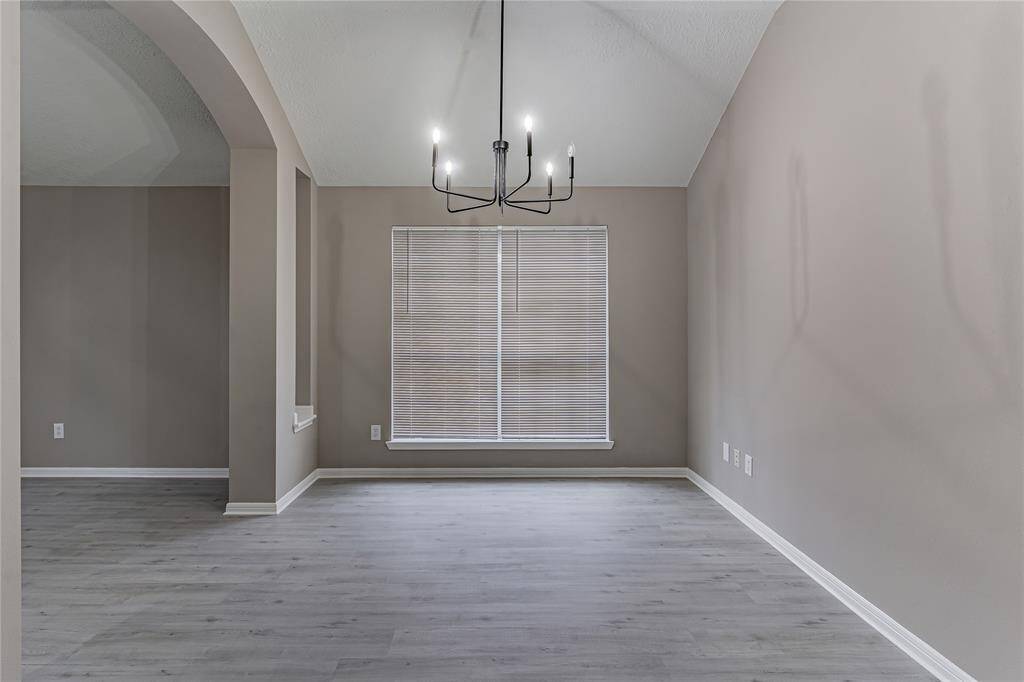 Elegant formal dining room with sleek flooring, soft neutral tones, and a modern chandelier—perfect for hosting memorable dinners.