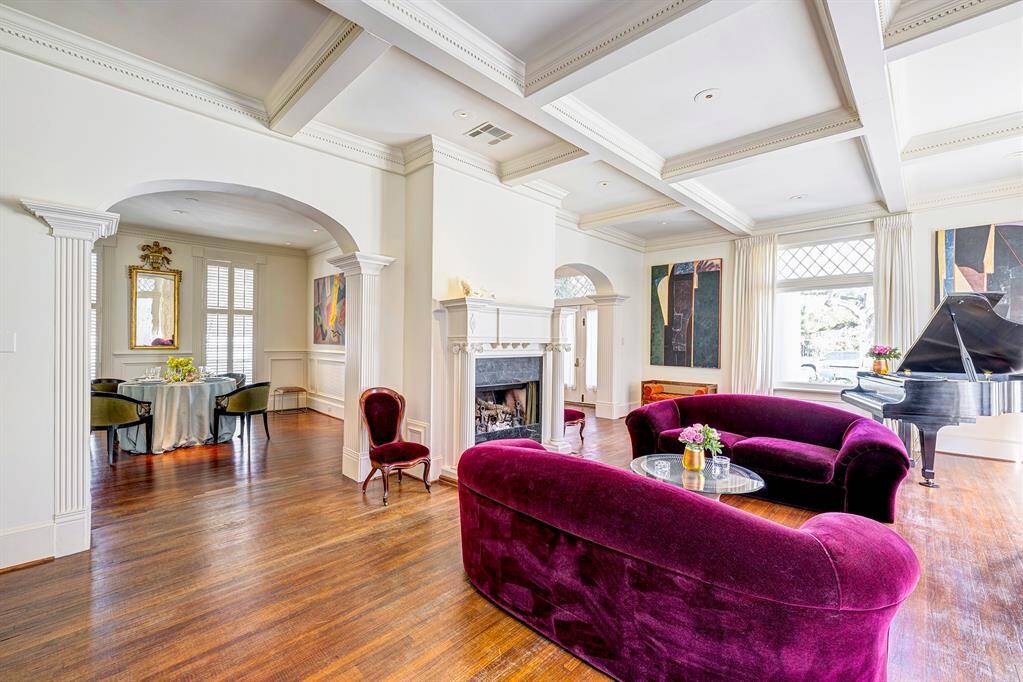 The living room, centered around its original fireplace with a classic wooden mantle, opens seamlessly into the dining room. Abundant natural light pours in through large windows, accentuating the open layout and highlighting the traditional architectural details. The harmonious design creates an inviting atmosphere, ideal for hosting gatherings or enjoying intimate family moments. The blend of charm and functionality makes this area a timeless and versatile space.