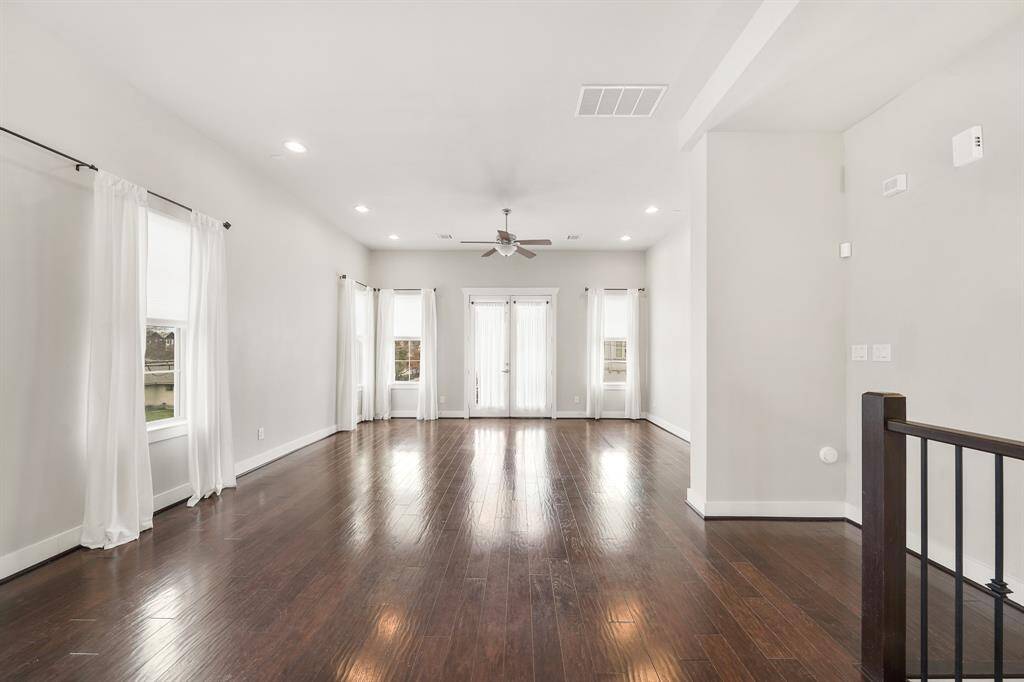 The living room features a high ceiling with recessed lighting, ceiling fan with lighting, pre-wiring for surround sound speakers & gleaming hardwood floors.