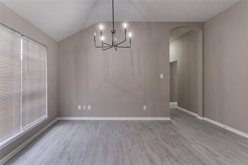 Elegant formal dining area with stylish chandelier and abundant natural light for perfect gatherings.
