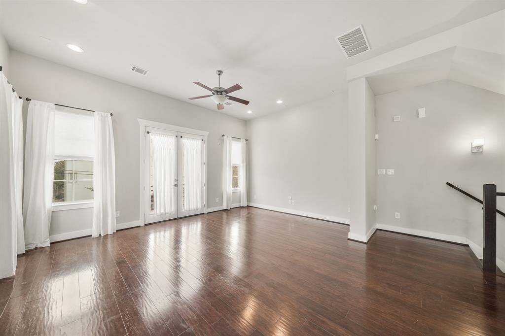 French doors flanked by windows with shades & draperies opens to a wrought iron balcony overlooking the front of the home.