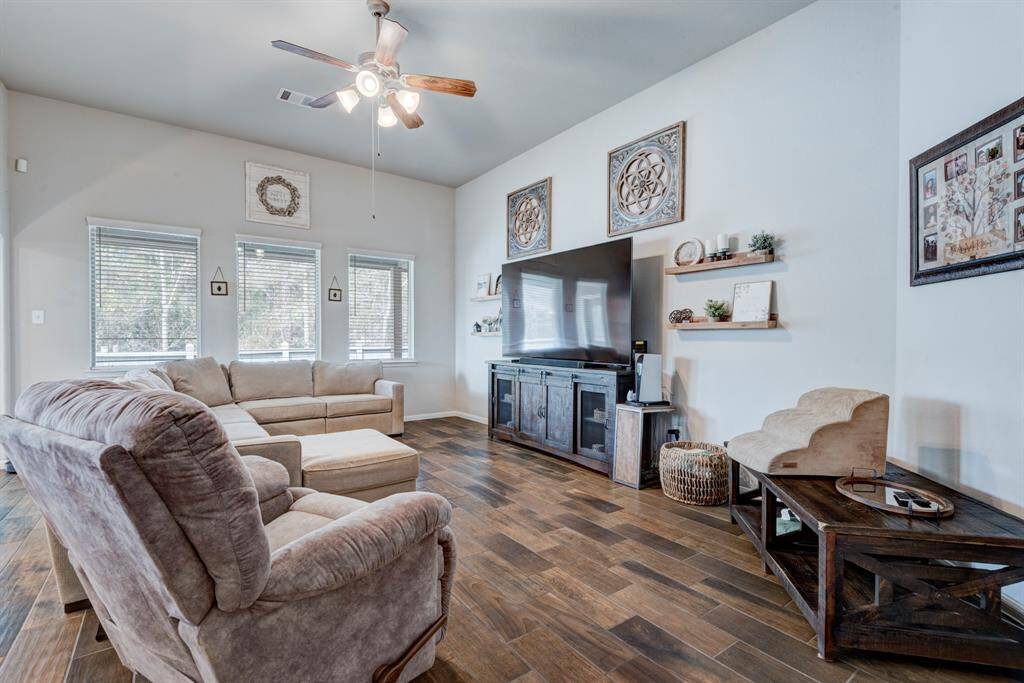 Family room has plenty of natural light, window coverings, ceiling fan, and wood look tile.