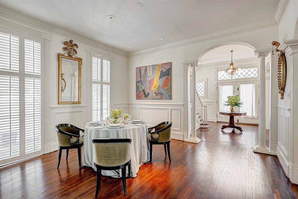 This dining room is a masterpiece of early 1900s design, featuring floor-to-ceiling windows that fill the space with soft, natural light. The original millwork is exquisitely detailed, including classic wainscoting and stately Greek pillars that add grandeur and sophistication.