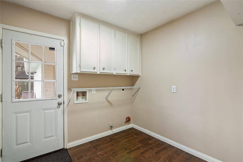 Enjoy the convenience of the utility room inside the home.  It features white upper cabinets for storage and space for a washer and dryer. The room has a neutral color scheme and wood-look flooring, providing a clean and functional space.