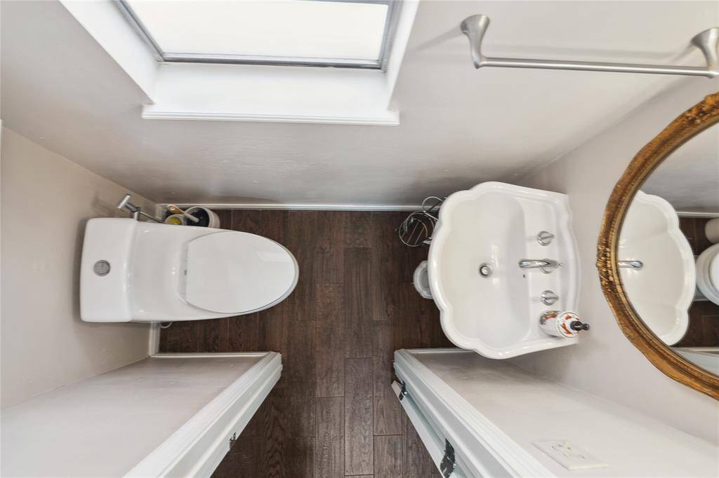 Half-bathroom featuring a modern toilet & a stylish pedestal sink located off the utility room and accessible via the backdoor.
