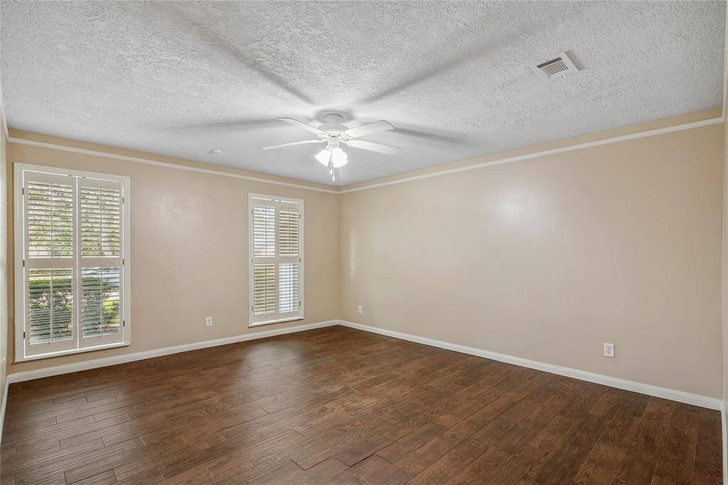 This master bedroom is on the first floor with tile flooring, and ample natural light from two large windows with shutters. A ceiling fan adds comfort to this inviting space.