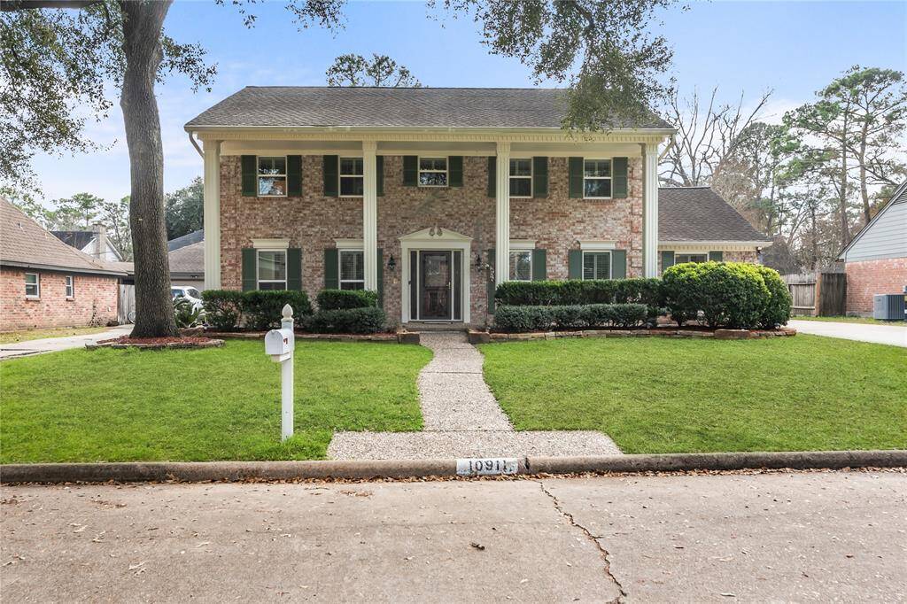 5 BR home with a well-maintained front yard with mature trees and a paved walkway leading to the entrance.