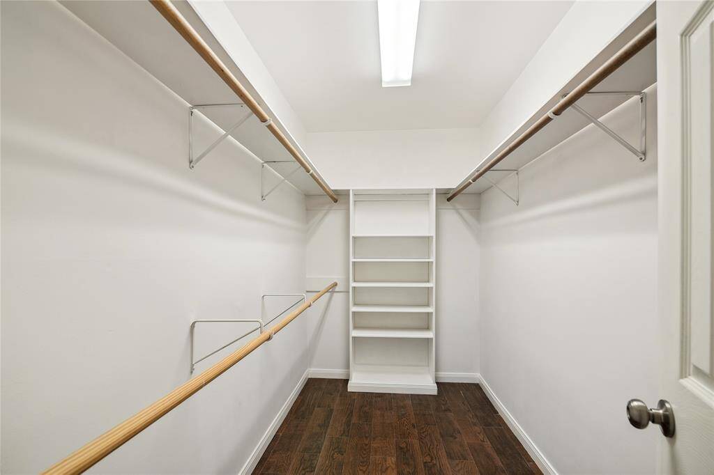 Master bedroom spacious walk-in closet with ample hanging space on both sides, and built-in shelving at the back for organized storage.