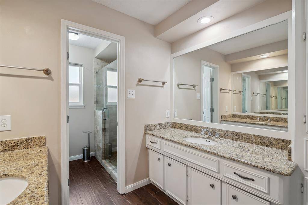 Master esuite with spacious layout, dual sinks on granite countertop vanities and updated glass enclosed walk-in shower.