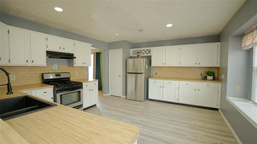 This kitchen features a spacious layout with light wood flooring and ample natural light. It includes modern stainless steel appliances, white cabinetry, and neutral countertops, offering a clean and inviting atmosphere.